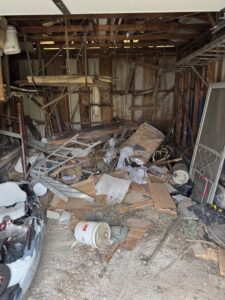A cluttered garage interior completely filled with junk and debris, awaiting removal by Trash & Dash in Houston, TX.