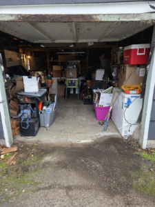 A cluttered garage filled with boxes, furniture, and appliances, awaiting junk removal services from Junk Management in Vancouver, WA.