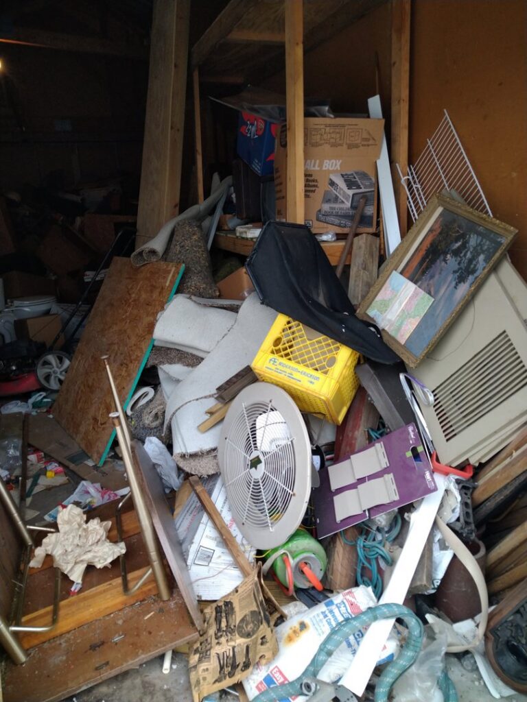 A cluttered garage interior filled with various items and debris, indicating a junk removal service by Kaveman Hauling LLC in Ankeny, IA.