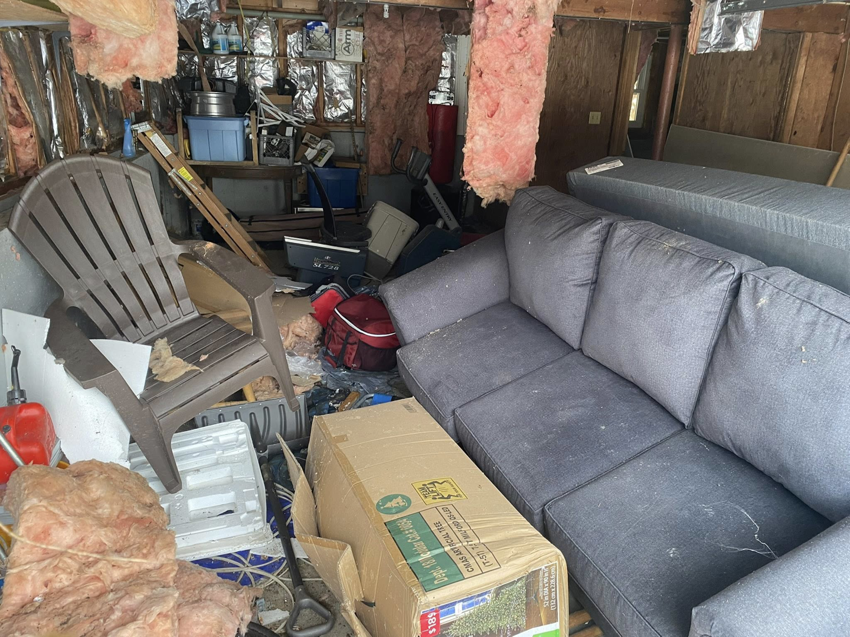 A cluttered garage filled with old furniture and debris, ready for junk removal by Trash King LLC in Derry, NH.
