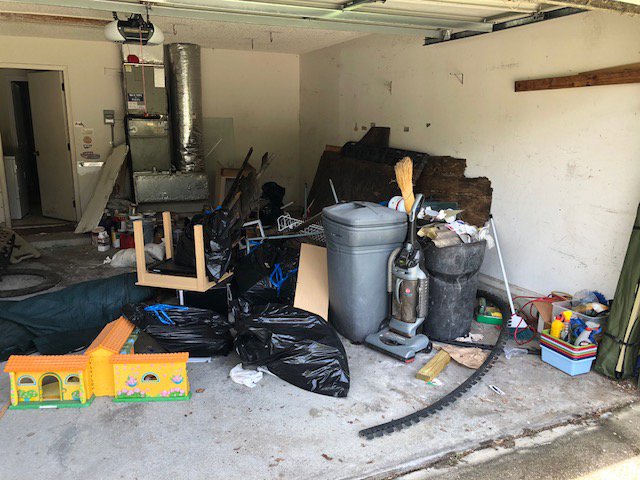 A cluttered garage filled with household junk, bags of trash, and old items, ready for a junk removal service by Trashouts Junk Removal in Pembroke Pines, FL.