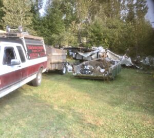 A cluttered garage packed with boxes, old tires, and various junk, showing a typical cleanout job by Tiny's Trash & Hauling Service L.L.C in Williamstown, VT