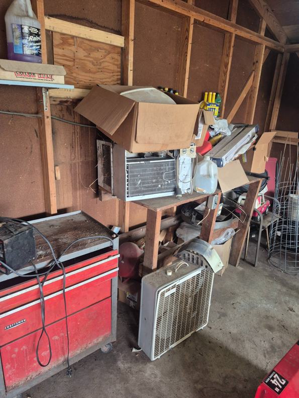 A cluttered garage or shed interior with old appliances, boxes, and tools, representing a cleanout by Siouxland Junk Removal in Sioux City, IA.