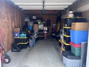 A cluttered garage or storage unit packed with plastic bins, boxes, and various items, awaiting junk removal by JOLTZ Junk Removal in Dayton, OH.