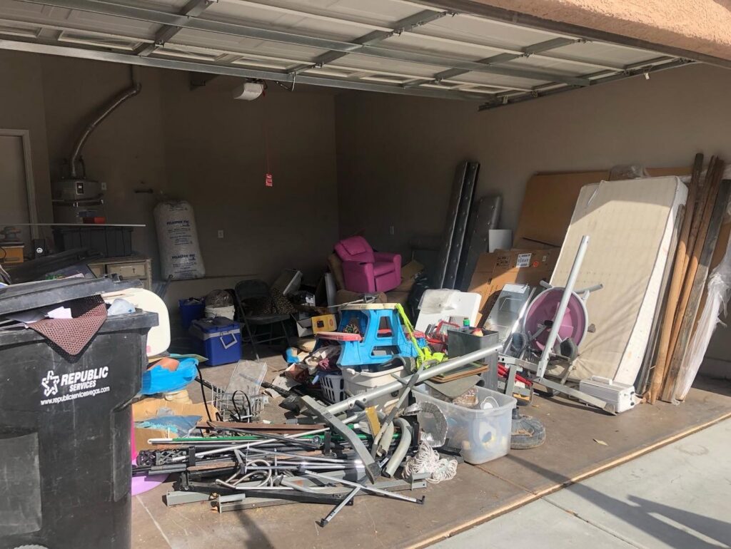 A very cluttered garage with a large pile of various items, including a treadmill and furniture, for junk removal by MLG Strong Hauling & Junk Removal LLC in Henderson, NV.