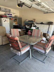 A cluttered garage filled with furniture, a mattress, and boxes, awaiting junk removal by Road Dogz Hauling in Las Vegas, NV.