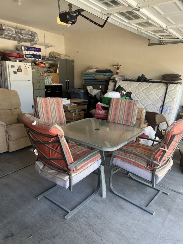 A cluttered garage filled with furniture, a mattress, and boxes, awaiting junk removal by Road Dogz Hauling in Las Vegas, NV.