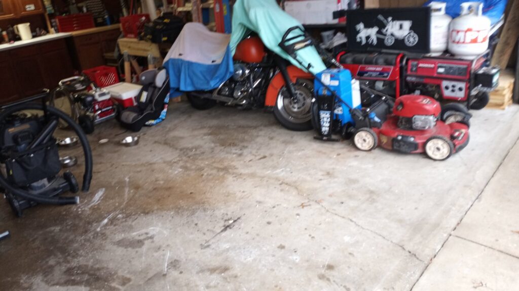A cluttered garage containing a motorcycle, lawnmower, and generator, indicating a space ready for junk removal by HAULA Junk Removal in Canton, OH.