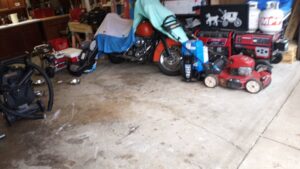 A cluttered garage containing a motorcycle, lawnmower, and generator, indicating a space ready for junk removal by HAULA Junk Removal in Canton, OH.