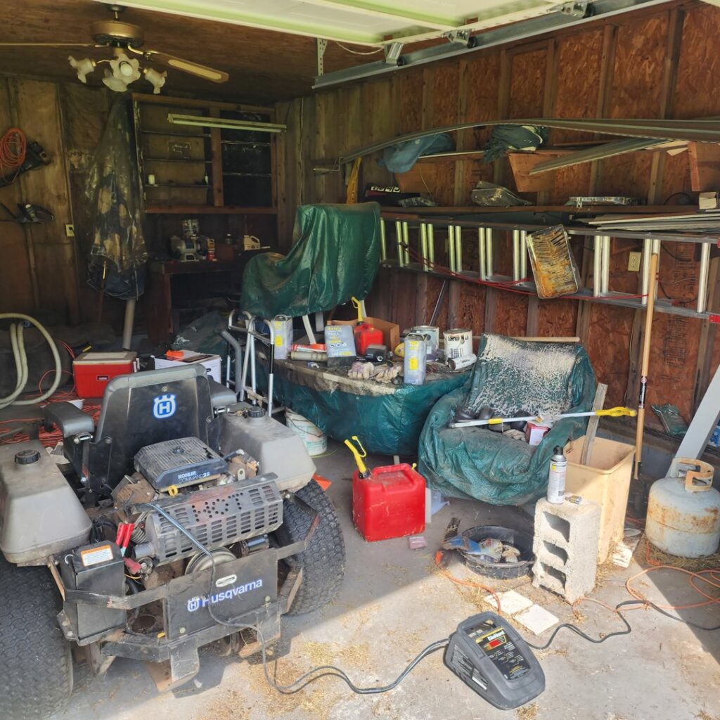 A cluttered garage with a riding mower and many items awaiting junk removal by Dumpzilla in Raleigh, NC.