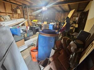 A heavily cluttered garage or workshop filled with tools and equipment, indicating a cleanout service by Big Sky Junk Removal LLC in Billings, MT.