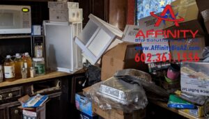 A kitchen heavily cluttered with boxes, appliances, and various items, depicting a junk removal project by Affinity Bio Solutions in Phoenix, AZ.