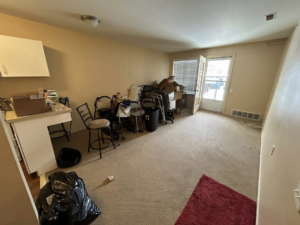 A cluttered living area with chairs, boxes, and a trash bag, awaiting junk removal from Big Joe's Junk removal Company LLC in Gibraltar, MI.