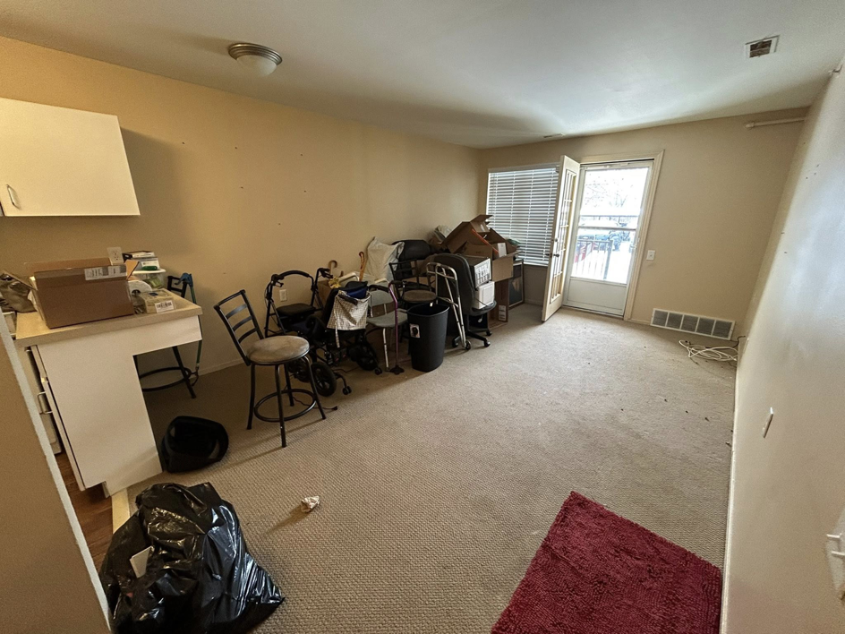 A cluttered living area with chairs, boxes, and a trash bag, awaiting junk removal from Big Joe's Junk removal Company LLC in Gibraltar, MI.