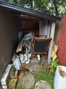 A cluttered outdoor storage area filled with an office chair, bricks, and various debris, ready for junk removal by Route Junk in Orlando, FL.