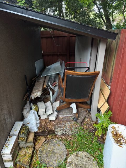 A cluttered outdoor storage area filled with an office chair, bricks, and various debris, ready for junk removal by Route Junk in Orlando, FL.