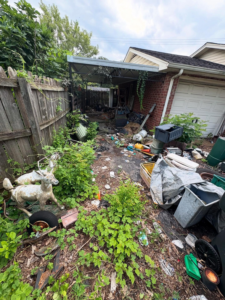 A cluttered and overgrown backyard filled with various junk and debris, ready for cleanup by Fargo's Junk Removal in Nashville, TN.