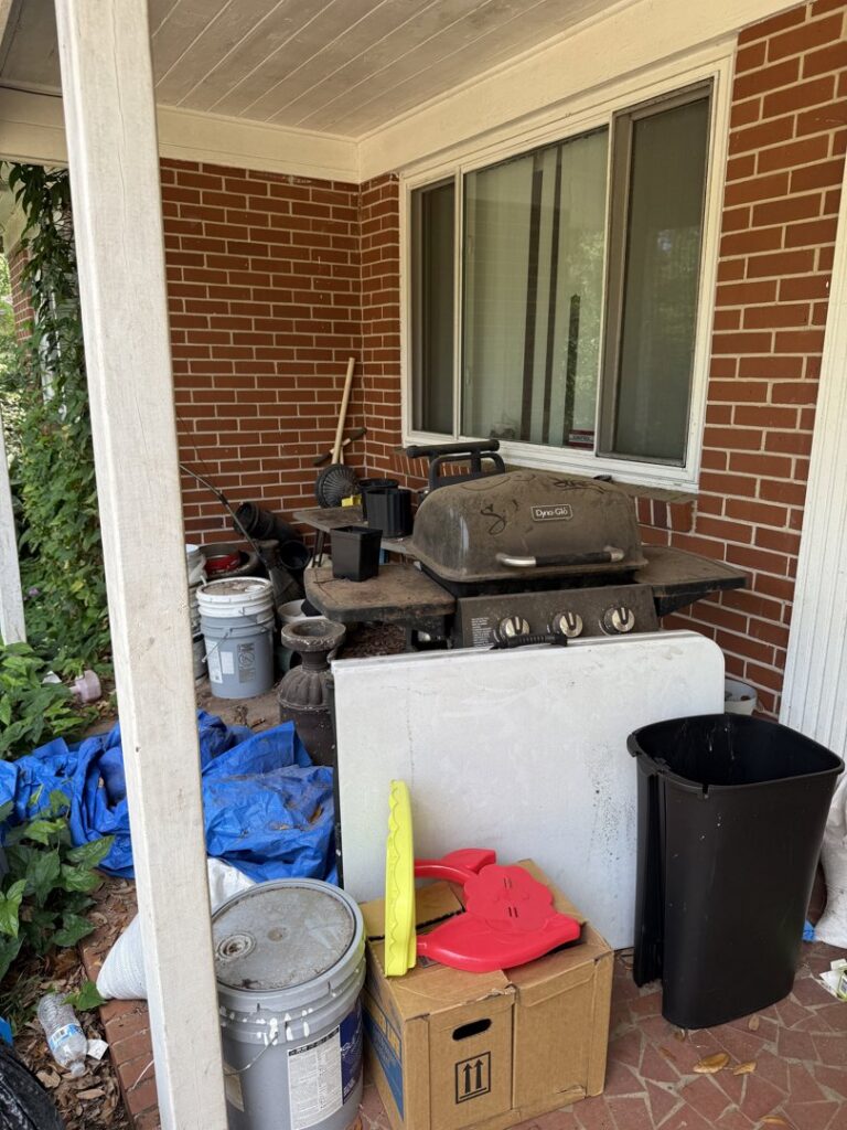 A cluttered patio area with an old grill, buckets, tarps, and various junk items ready for removal by Reliable Pro in Tallahassee, FL.