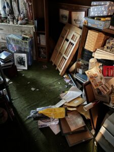 A heavily cluttered room with boxes, papers, and miscellaneous items, indicating a cleanout service by Junkin Irishman in Wayne, NJ.