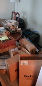 A cluttered room filled with boxes, bags, and various items, representing a 'before' scene for junk removal by Junk Fade Away, LLC in Jacksonville, FL.