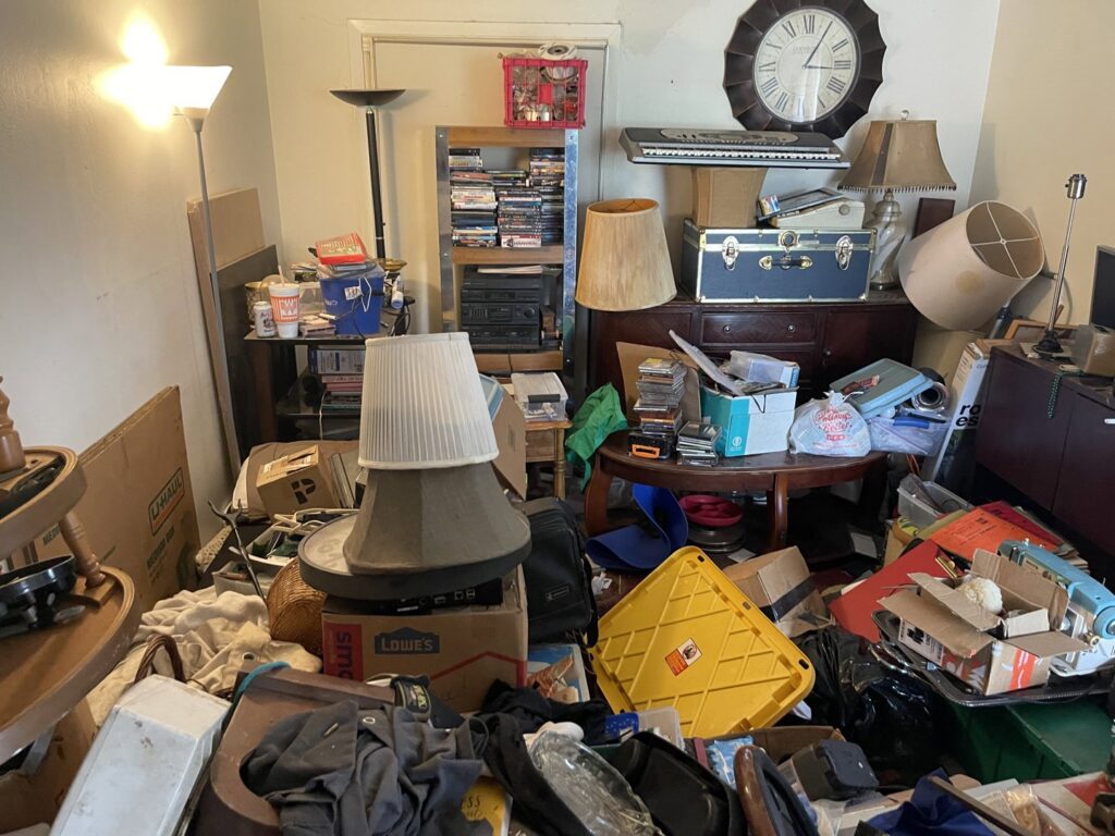 A heavily cluttered indoor room filled with furniture, boxes, and various items, awaiting junk removal service from JunkStart in San Antonio, TX.