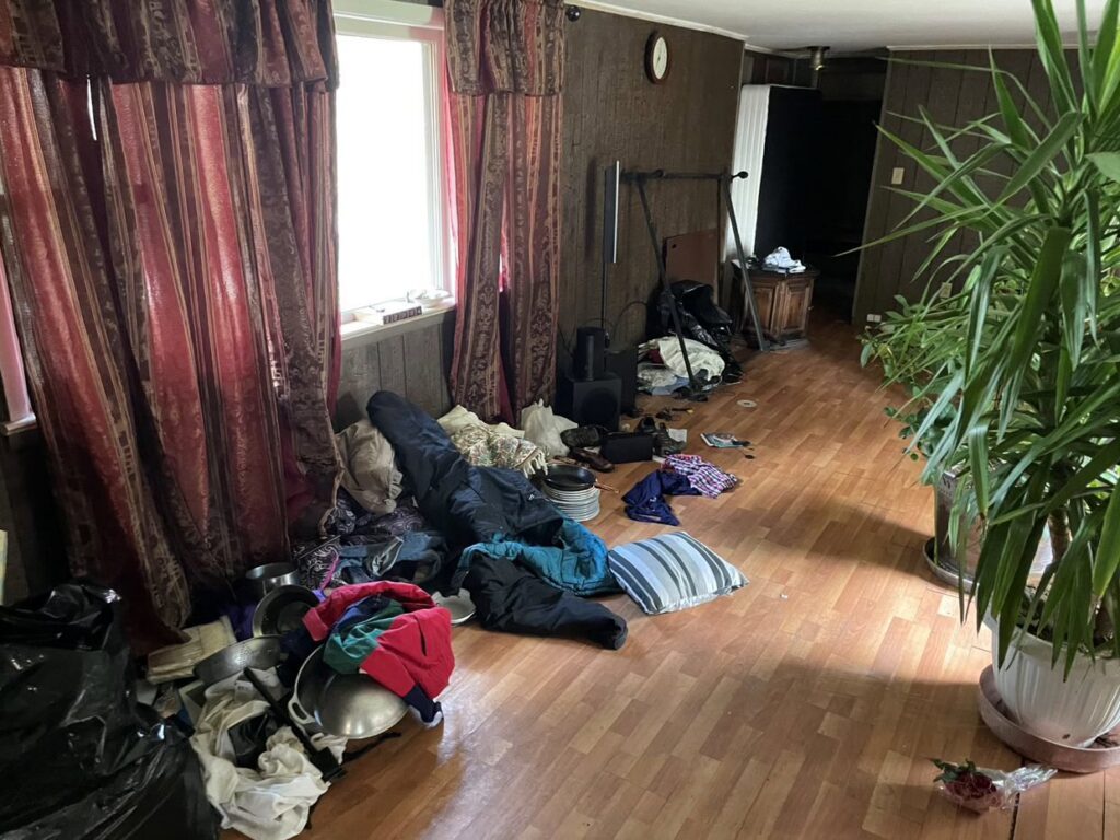 A cluttered room with clothes and various items on the floor, indicating a space ready for cleanout by Removall Residential and Commercial Cleanout Services in York, PA.