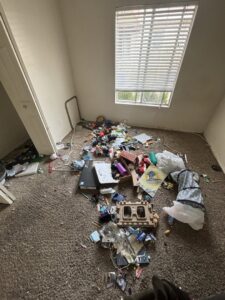 A cluttered room with various debris scattered on the floor, indicating a cleanout job by YEE-HAul Trash Removal in St. George, UT.