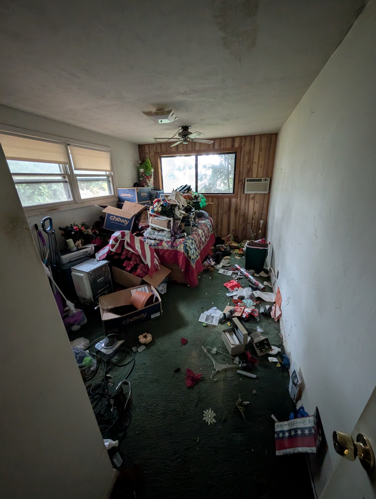 A heavily cluttered room filled with boxes and items, showing a cleanout job by Patriot Hauling & Junk Removal LLC in Salem, OR.