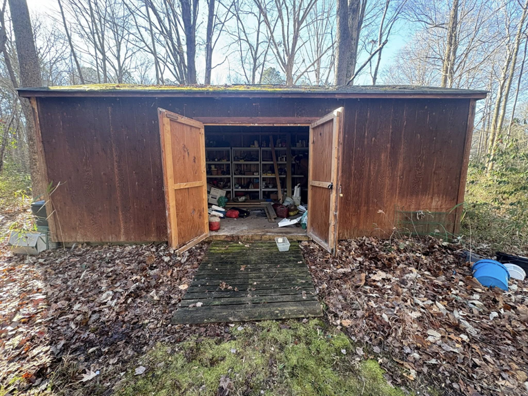 An open shed revealing a cluttered interior, showing a shed cleanout service by EcoClear Junk Removal in Baltic, CT.