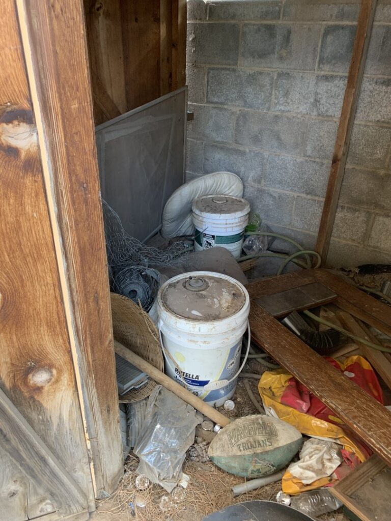 A cluttered shed corner with buckets, wire mesh, and wood scraps, ready for cleanout by Roadrunner JunkSmart Solutions LLC in Las Cruces, NM.