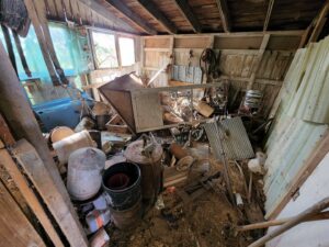 The interior of a cluttered shed filled with old items and debris, indicating a general junk removal and cleanout service by Top Tier Waste Services LLC in Lancaster, OH