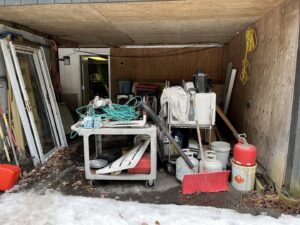 A cluttered shed or carport filled with various items before a cleanout service by Tj's junk removal LLC in Derry, NH.