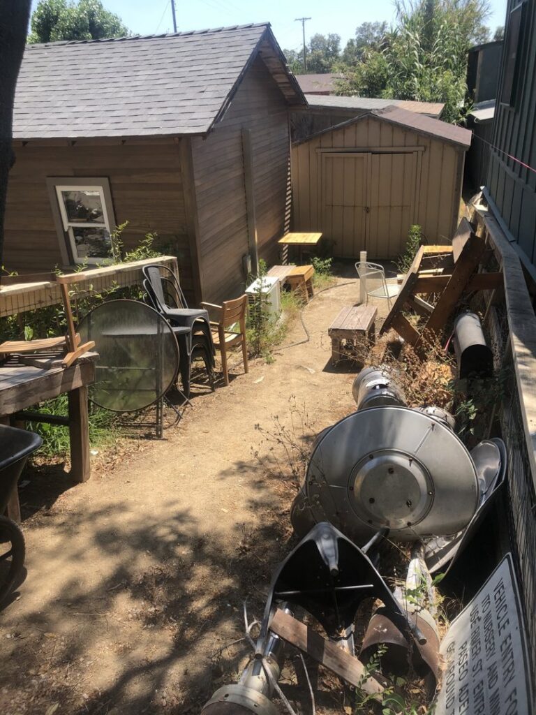 A cluttered side yard with various old items and debris awaiting junk removal by The Junk Gentlemen in Anaheim, CA.