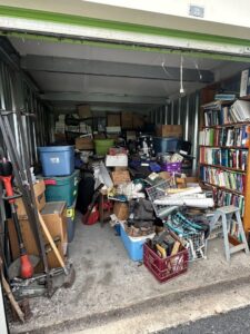 A cluttered storage unit filled with boxes and various items, ready for cleanout by SATX Junk-A-Haulics in San Antonio, TX.