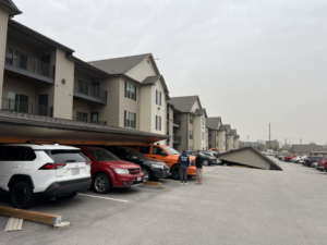 A collapsed carport structure at an apartment complex, showing damage requiring repair by Larson Exteriors in Sunset Hills, MO.