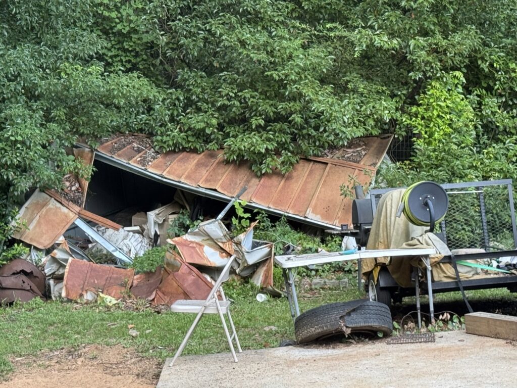 A collapsed metal shed surrounded by debris, indicating a demolition and removal job by L.P.Z Trash & Junk Removal in Tallahassee, FL.