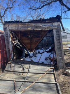A collapsed and dilapidated shed with debris and snow inside, indicating a demolition and junk removal service by Prestige Junk Removal & Hauling in Detroit, MI.