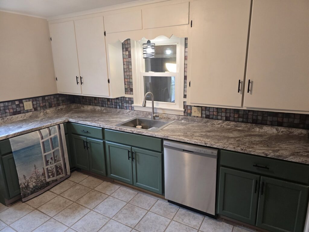 A vibrant kitchen renovation with white upper and green lower cabinets, new countertops, and a tiled backsplash by Ben Nye The Fix-It Guy in Erie, PA.