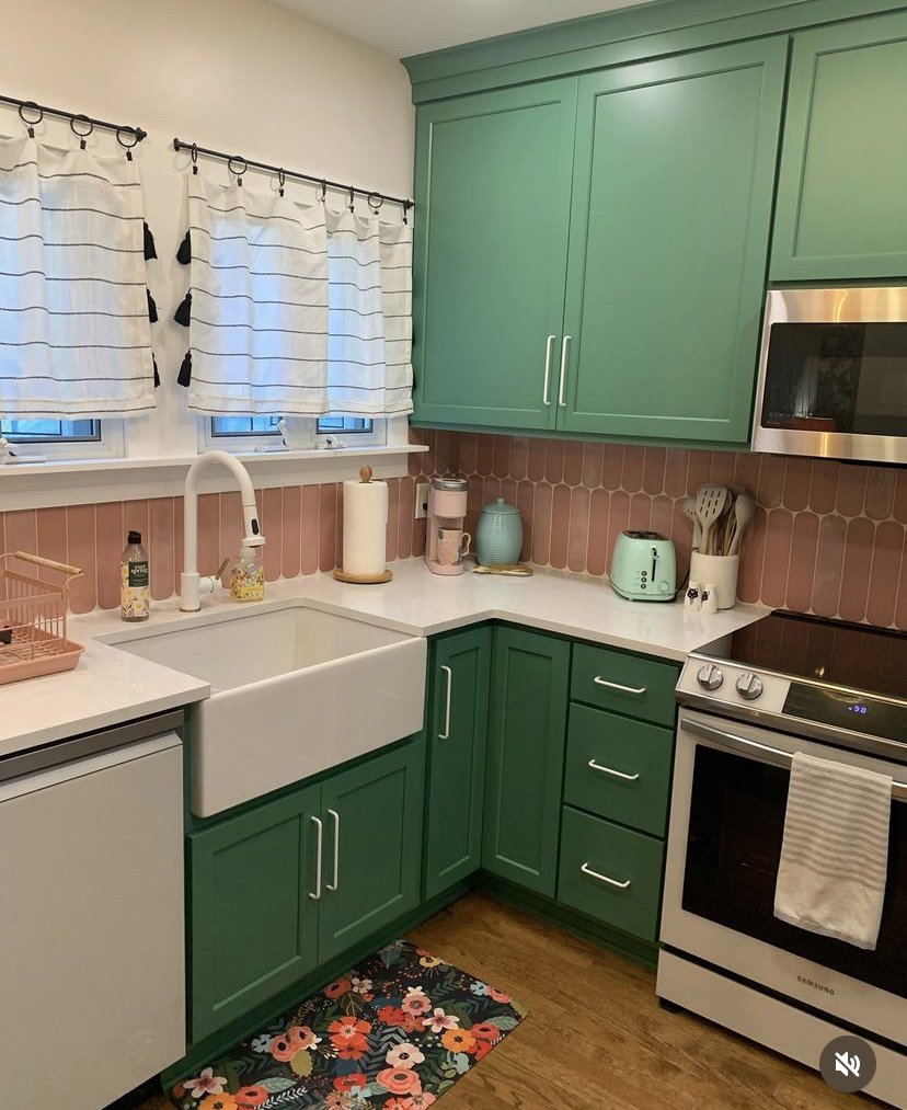 A vibrant kitchen remodel with green cabinets, a pink tile backsplash, and a farmhouse sink completed by CLE Remodeling Co in Cleveland, OH.