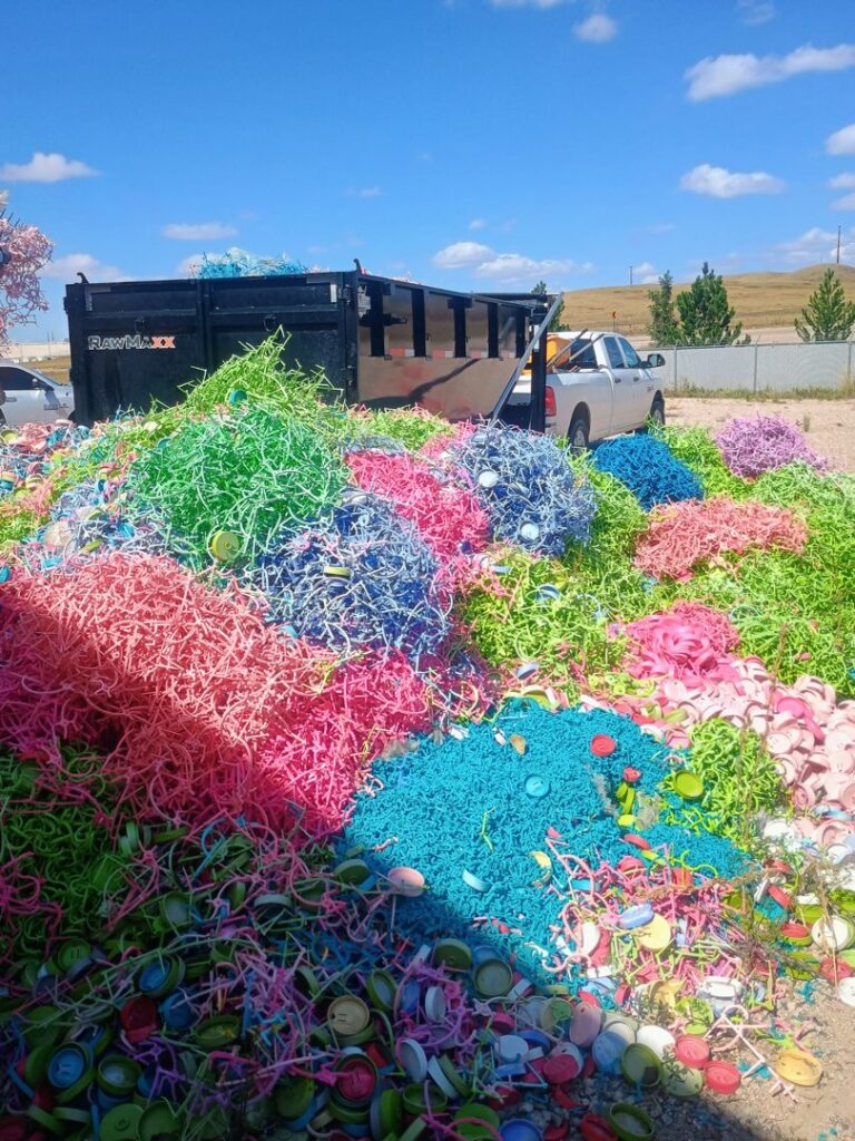 A large pile of colorful waste and plastic caps with a dump trailer for T-Rex Service LLC in Cheyenne, WY.