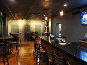 A completed commercial bar renovation with a long counter and stone accent wall by Mainville Construction & Remodeling LLC in Newington, CT.