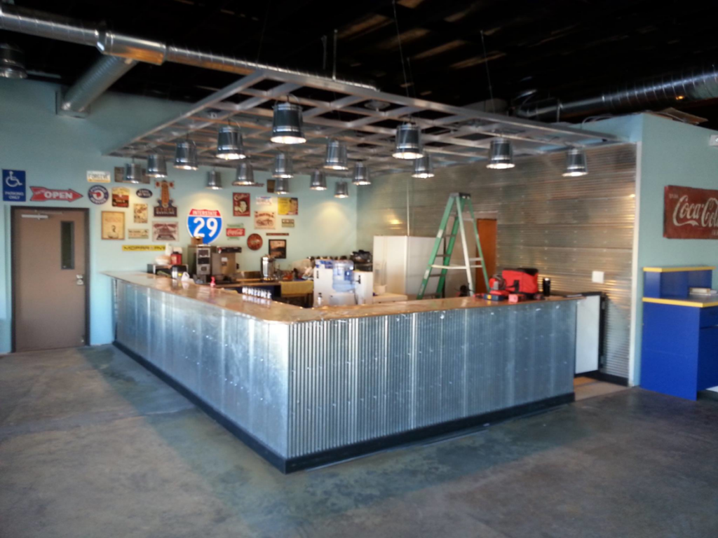 A commercial bar area undergoing renovation with a corrugated metal counter and industrial lighting by Work Horse Contracting in West Fargo, ND.