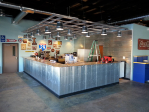 A commercial bar area undergoing renovation with a corrugated metal counter and industrial lighting by Work Horse Contracting in West Fargo, ND.
