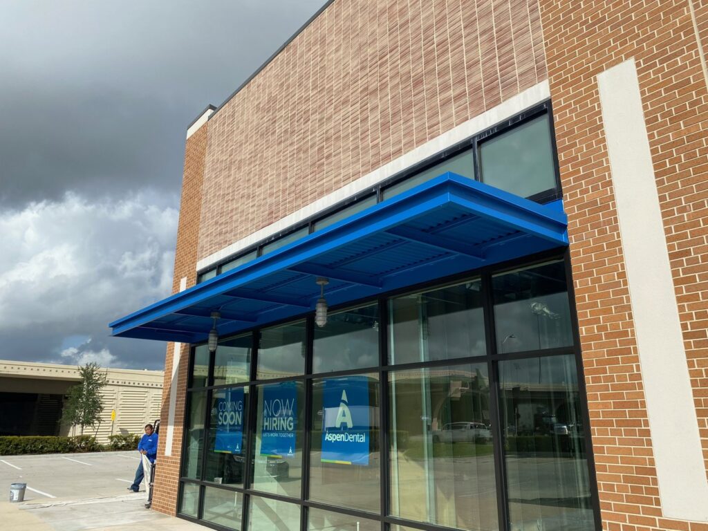 A newly installed blue awning on a commercial building exterior, showcasing general contractor work by Spectrum Paint and Commercial Services, Inc. in Houston, TX.