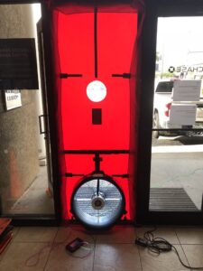 A blower door test setup in a commercial building's glass doorway by Green Energy Testing in Tampa, FL.