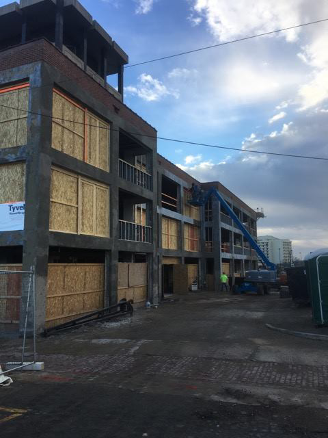 Exterior view of a commercial building construction site with a lift and worker, managed by Kemna Restoration & Construction in Indianapolis, IN.