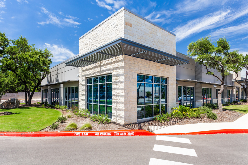 Exterior view of a modern commercial building with stone and glass facade, completed by Drash Contracting Company LLC in San Antonio, TX.