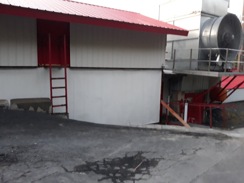 An industrial building exterior with a red ladder, suggesting commercial handyman services by Phoenix's Cleaning Service, LLC in Rutland, VT.