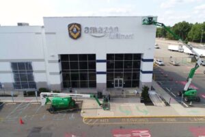 Workers on boom lifts performing exterior painting at an Amazon fulfillment center by Alpine Painting and Sandblasting Contractors in Paterson, NJ.