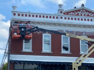 Workers in a JLG lift performing exterior painting and repair on a commercial building by Usa Construction of Danbury LLC in Danbury, CT.